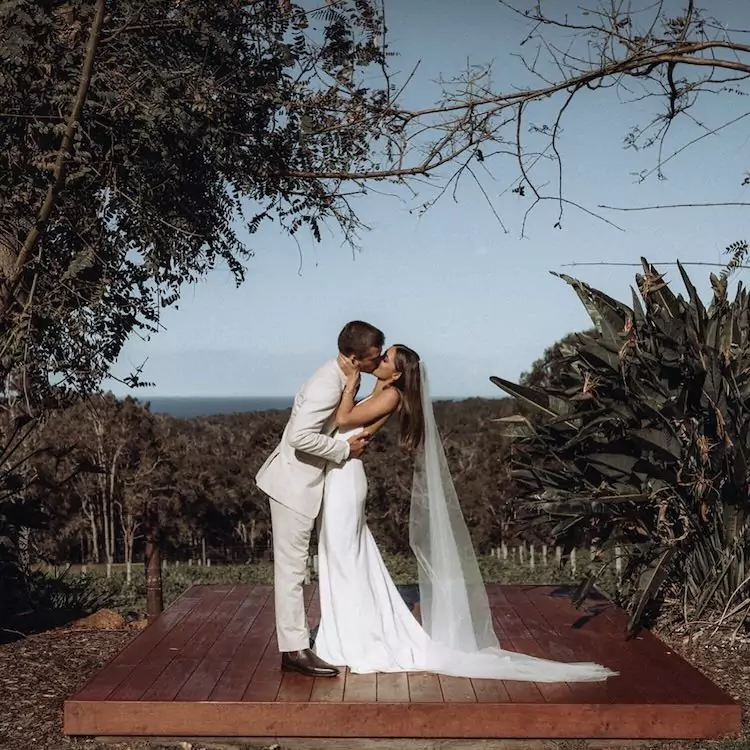 Bride and groom kissing on the platform in the garden during their wedding