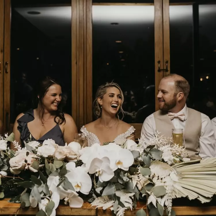 Bride, groom, and maid of honour smiling during a wedding reception in the restaurant